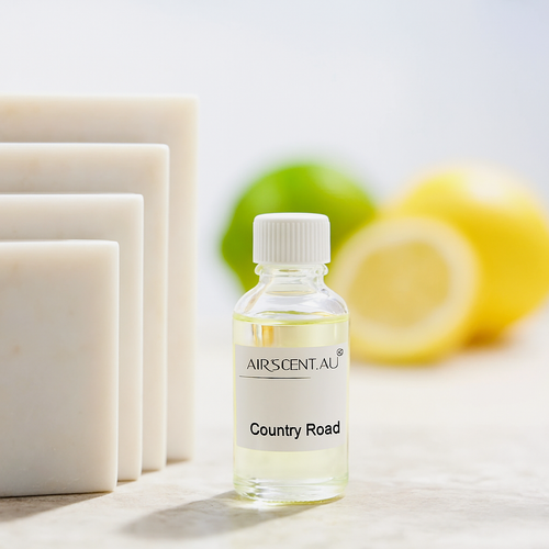 Bottle of AIRSCENT.AU 'Country Road' oil with soap bars and lemons in the background